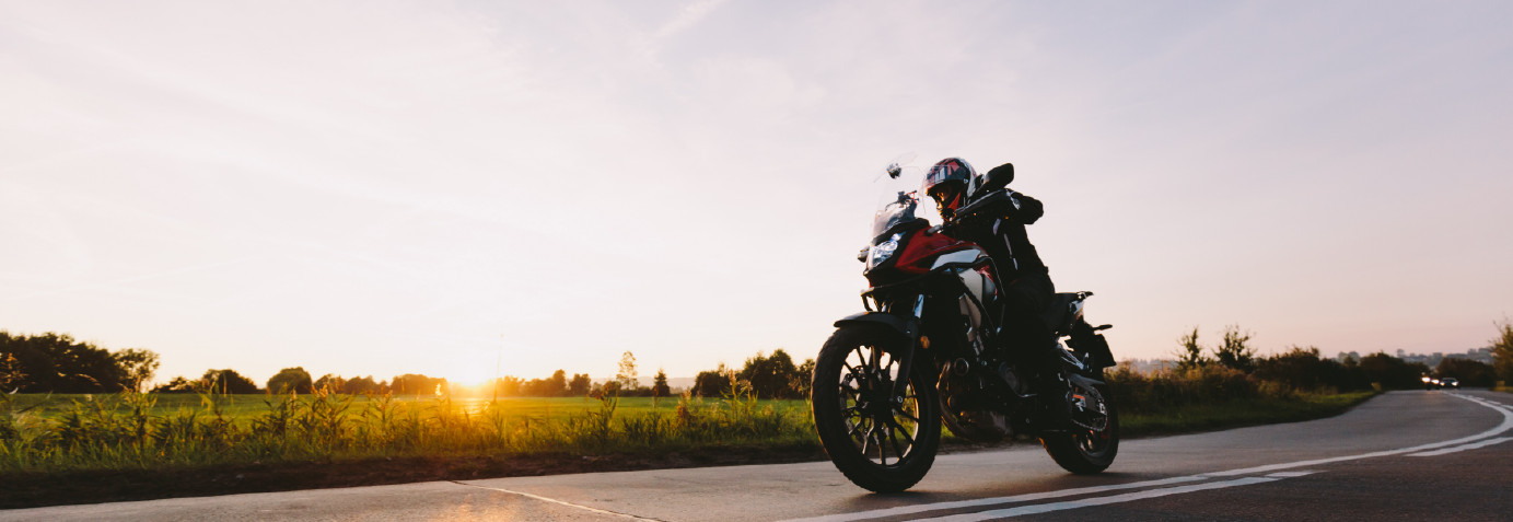 A motorcycle on a scenic open road with a sunset in the back, perfect for those considering a motorcycle loan.