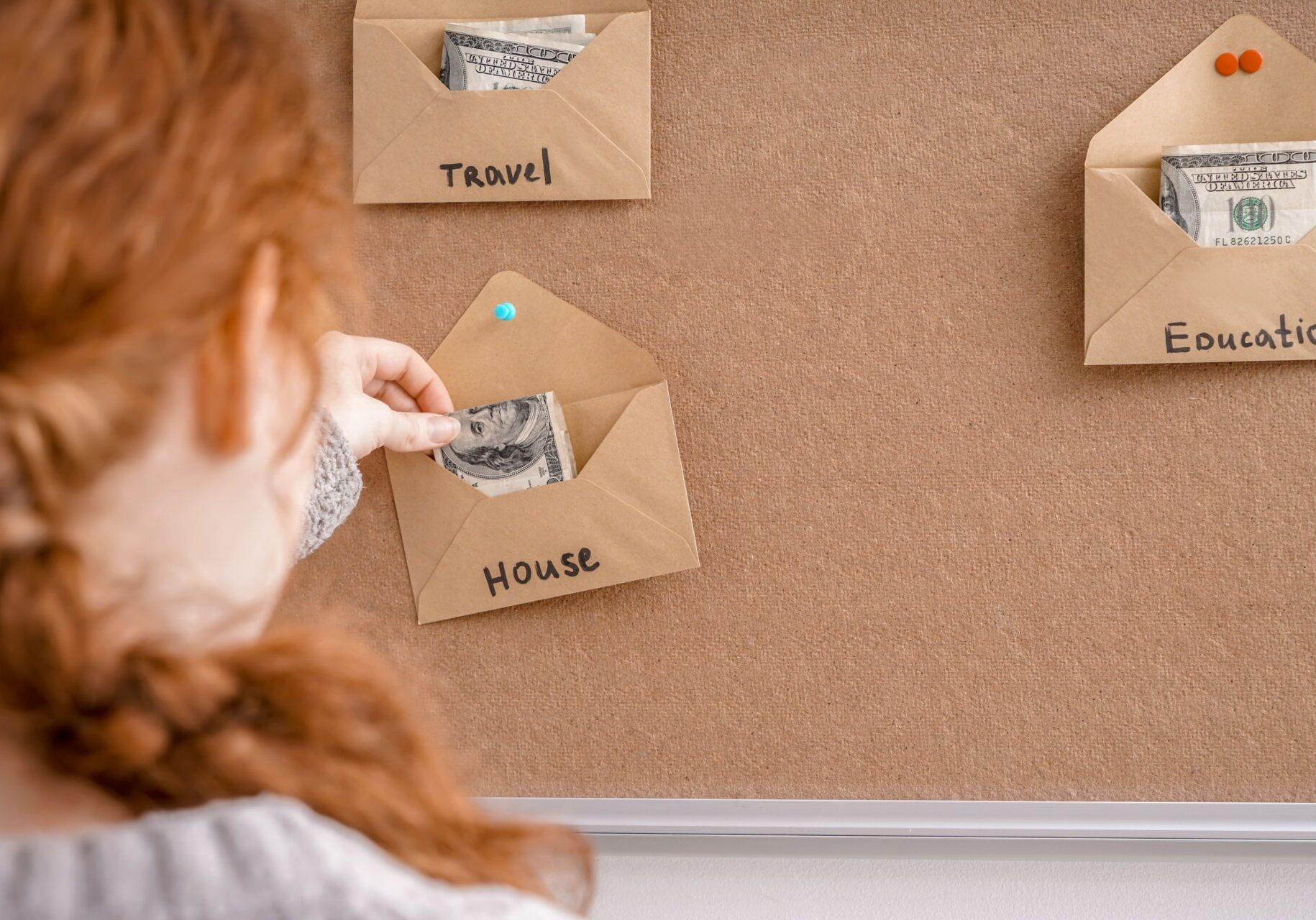 Woman putting money in envelopes for different needs. Concept of saving in a Club Savings Account.